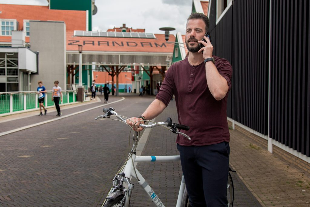 Collega belt, met fiets aan de hand, nabij station Zaandam