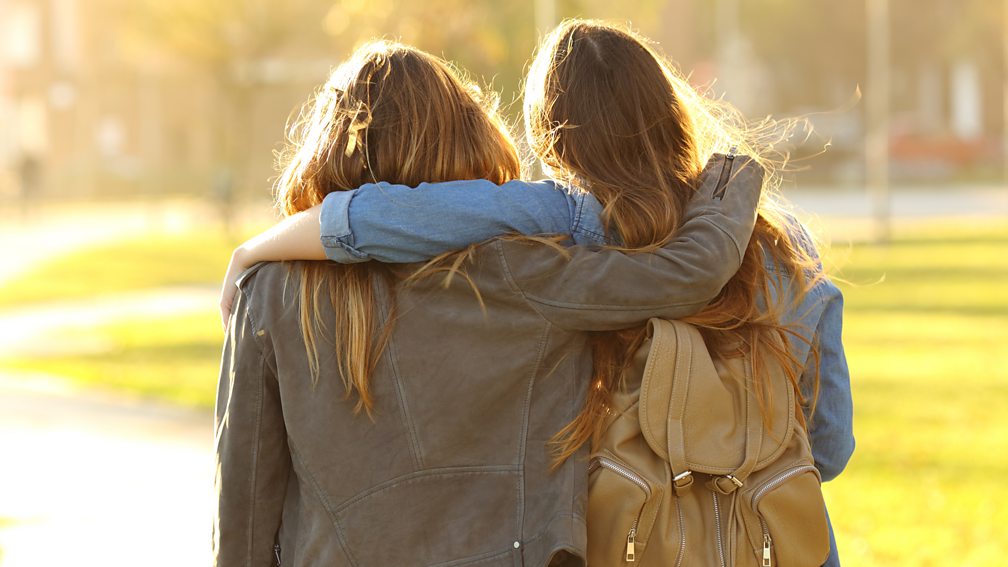 Twee vrouwen omhelzen elkaar. Van achteren gefotografeerd